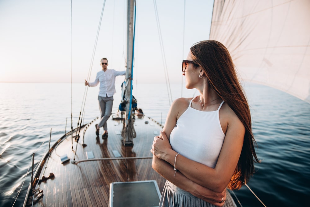 beaufiful female standing on the yacht and looking to her sugar daddy