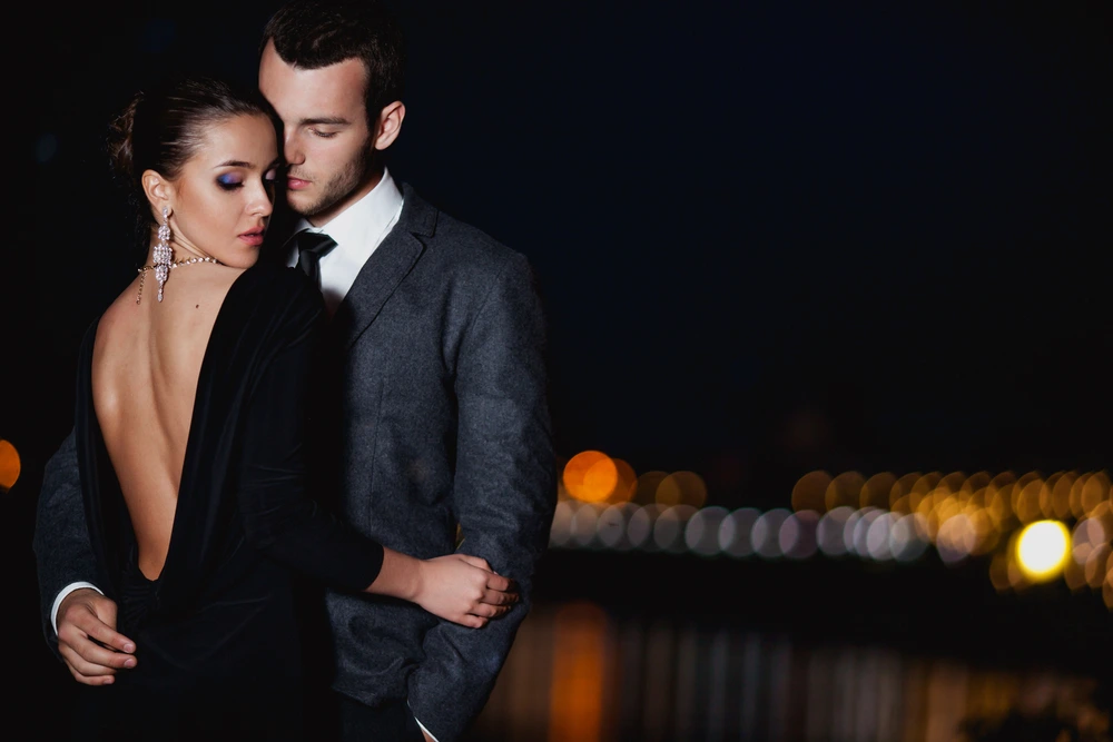 Elegant couple embracing on a romantic night with city lights in the background