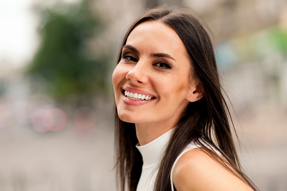 Selbstbewusste lächelnde Frau mit natürlicher Ausstrahlung als Symbol für Verführung und Anziehung