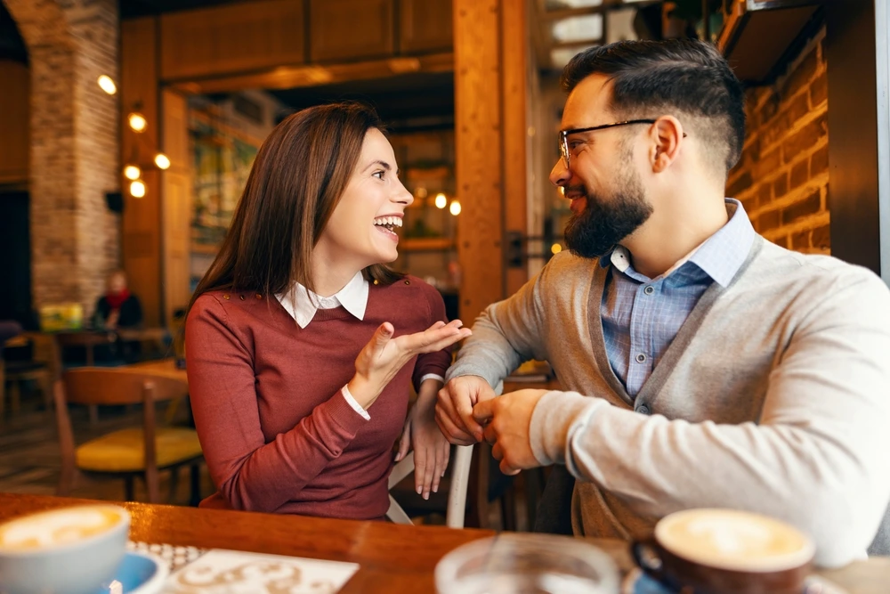 Ein glückliches Paar unterhält sich intensiv und ehrlich in einem gemütlichen Café bei einer Tasse Kaffee – Symbol für klare Kommunikation beim Dating.