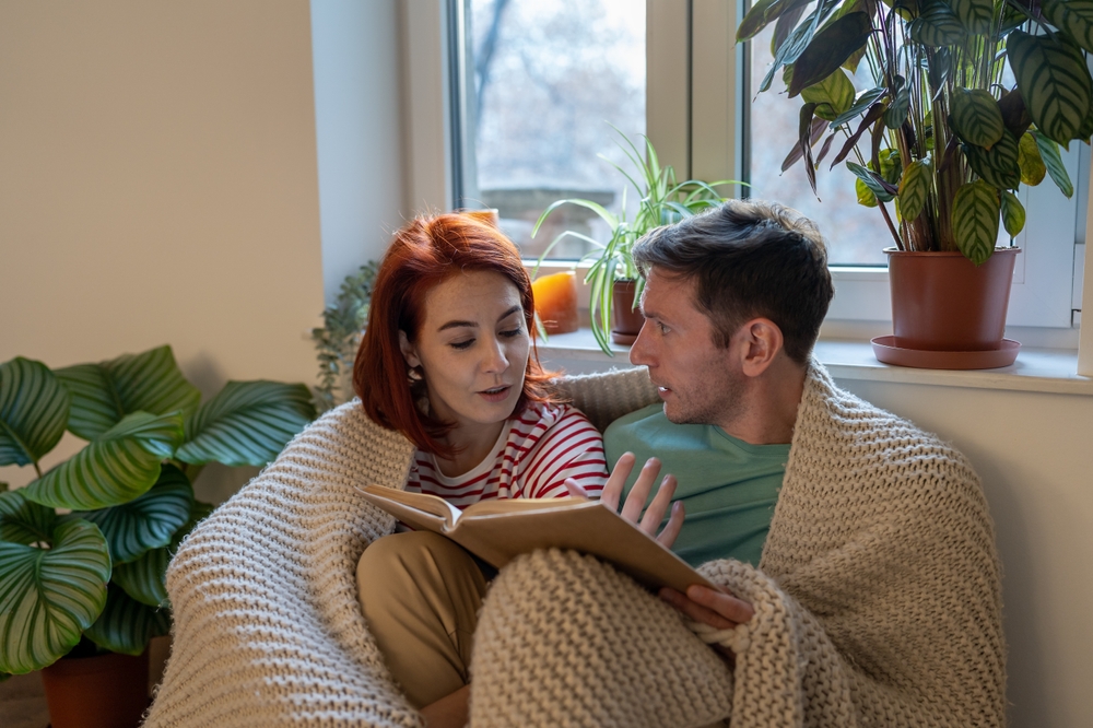 Paar spricht zu Hause ueber ein Buch und gemeinsame Interessen